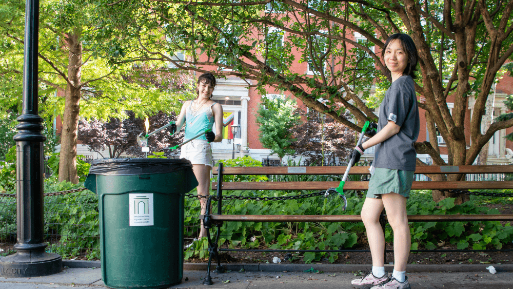 Two volunteers hold trash grabbers in Washington Square Park