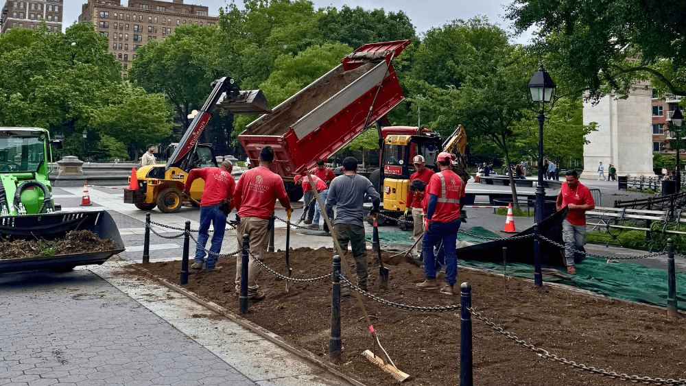 People use tools and vehicles to do landscaping work in Washington Square Park.