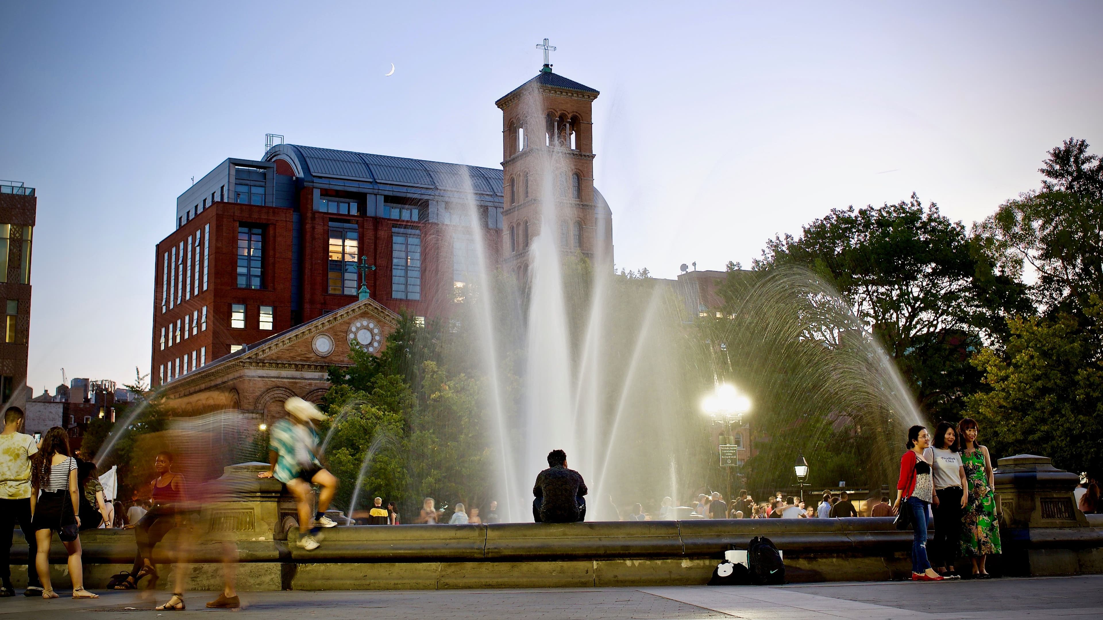 People sit in front of the Washington Square Fountain.