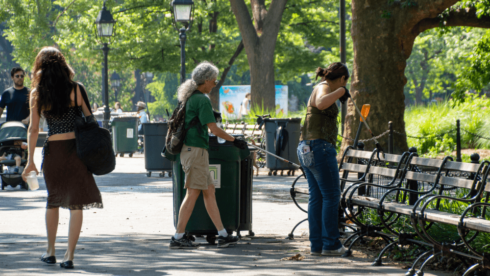 Two people clean up garbage in Washington Square Park.